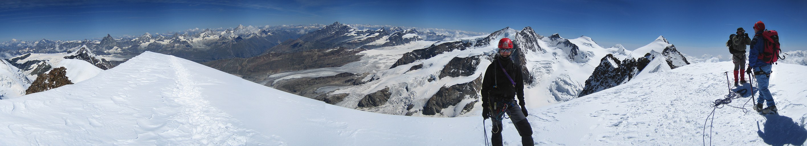Lyskamm ridge traverse and Castor: Daniel, Claus-Dieter, and Rainer on top of Lyskamm West; in the background from left to right: Mont Blanc, Grand Combin, Dent d'Herens, Matterhorn, Dent Blanche, Grand Cornier, Obergabelhorn, Zinalrothorn, Weisshorn, Gornergrat ridge, Taschhorn, Jungfrau (far back at the horizon), Rimpfischhorn, Allalinhorn, Strahlhorn, Nordend, Dufourspitze (with Grenzgletscher), Zumsteinspitze, Signalkuppe, Parrotspitze, and Lyskamm East summit Lyskamm ridge traverse and Castor: Daniel, Claus-Dieter, and Rainer on top of Lyskamm West; in the background from left to right: Mont Blanc, Grand Combin, Dent d'Herens, Matterhorn, Dent Blanche, Grand Cornier, Obergabelhorn, Zinalrothorn, Weisshorn, Gornergrat ridge, Taschhorn, Jungfrau (far back at the horizon), Rimpfischhorn, Allalinhorn, Strahlhorn, Nordend, Dufourspitze (with Grenzgletscher), Zumsteinspitze, Signalkuppe, Parrotspitze, and Lyskamm East summit